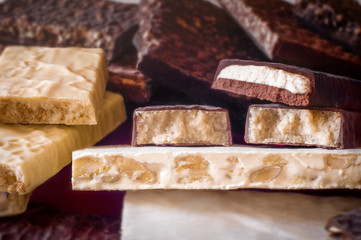 Turron. Festive sweets. Warm sunlight. Selective focus. Blurred background. Traditional Spanish Christmas candy. Torrone and nougat with nuts. Texture, layers.