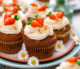 Carrot cupcakes with mascarpone cream decorated with marzipan carrots on a plate. Delicious homemade dessert