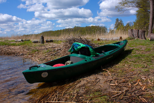 a kayak with a jacket stands on the bank of the river