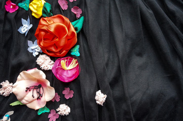 Silk colorful flowers over black fabric background