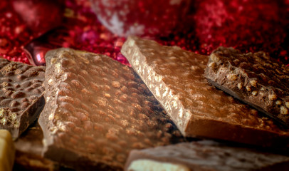 Turron. Festive sweets. Warm sunlight. Selective focus. Blurred background. Traditional Spanish Christmas candy. Torrone and nougat with nuts. Christmas tree decorations in the background.