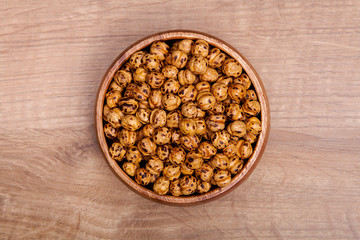 Roasted and dry chickpeas in a bowls on wooden table.