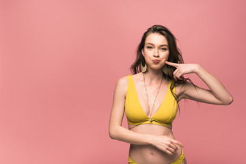 front view of pretty young woman in yellow swimsuit isolated on pink