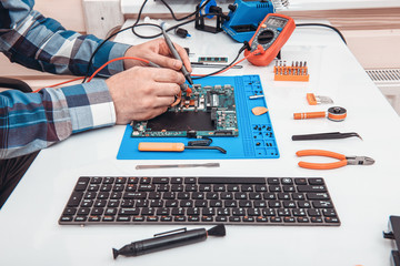 The repairman works in technical support, is engaged in the restoration and cleaning of the laptop.