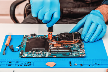 The repairman works in technical support, is engaged in the restoration and cleaning of the laptop.