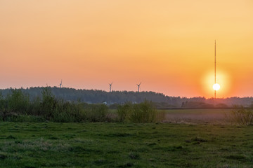 Fototapeta premium Beautiful orange sunset on the background of the forest, wind turbines. Beautiful nature outside the city