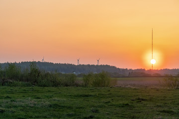 Beautiful orange sunset on the background of the forest, wind turbines. Beautiful nature outside the city