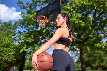 Beautiful sexy fitness girl in black sport wear with perfect body with basket ball at basketball court. Sport, fitness, lifestyle concept