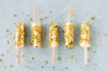 Mango and Pistachio Kulfi Lollies on Blue Cement Background