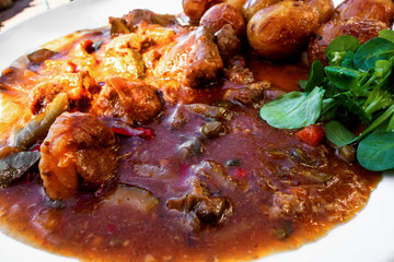 Lamb meat in wild vegetable sauce, potato and leaf.