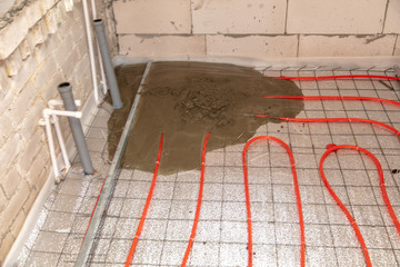 A worker pours concrete underfloor heating in the room