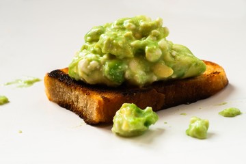 Avocado spread on toast, leftovers on white.