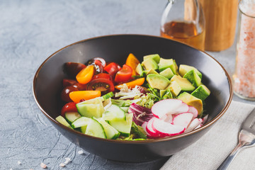 Vegan buddha bowl. Healthy vegetarian salad with cherry tomatoes, cucumber, radish,, avocado and lettuce.