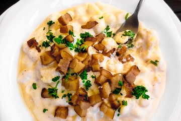 Potato dumpling with cheese, diced bacon, plate.