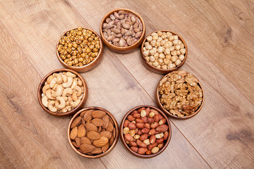 Different mixed nuts in a  bowls on wooden table. Healthy food and snack.