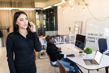 Joyful young businesswoman having negotiations by phone in office