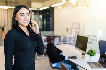 Joyful young businesswoman having negotiations by phone in office