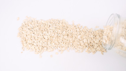 Pouring white oat flakes from glass jar