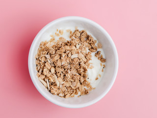 Whole grains on yogurt in white bowl, pink background.