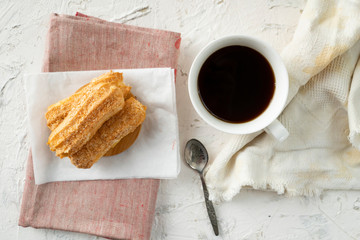morning snack with coffe and creamy eclair on a table with white tablecloth, business breakfasts