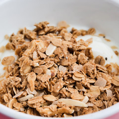 Whole grains on yogurt in white bowl, pink background.