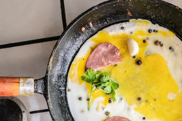 close up process of cooking scpambled eggs in a hot oiled frying pan with pepper and herbss