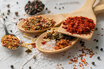 several spoons with mix variaty of different spices poured on the tables