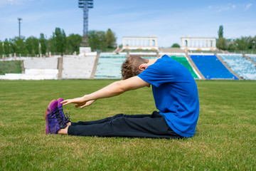 Fototapeta na wymiar sportsman doing stretching exercise on the stadium before summer practices