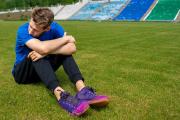 Naklejka premium tired male athlete sportsman relax on the grass field after practices