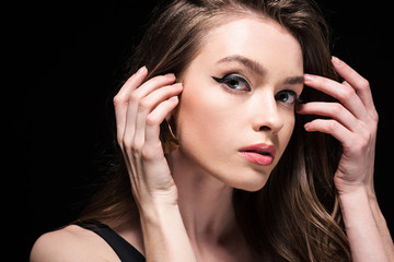 Obraz premium attractive young woman in underwear touching hair and looking at camera isolated on black