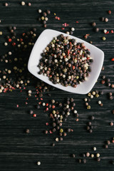 Mix of peppercorns in white bowl on wooden background