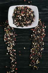 Mix of peppercorns in white bowl on wooden background