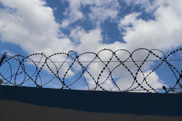 Blue sky through barbed wire