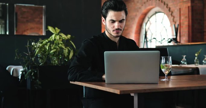 Successful handsome businessman using laptop at restaurant