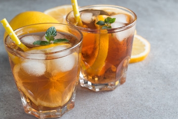 Glasses of cold ice tea with lemon, ice, mint on background. Homemade lemonade. Spring and summer drinks and beverages concept.