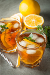 Glasses of cold ice tea with lemon, ice, mint on background. Homemade lemonade. Spring and summer drinks and beverages concept.