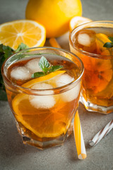 Glasses of cold ice tea with lemon, ice, mint on background. Homemade lemonade. Spring and summer drinks and beverages concept.