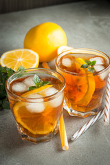 Glasses of cold ice tea with lemon, ice, mint on background. Homemade lemonade. Spring and summer drinks and beverages concept.