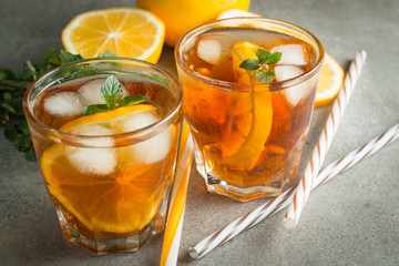 Glasses of cold ice tea with lemon, ice, mint on background. Homemade lemonade. Spring and summer drinks and beverages concept.