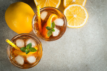 Glasses of cold ice tea with lemon, ice, mint on background. Homemade lemonade. Spring and summer drinks and beverages concept.