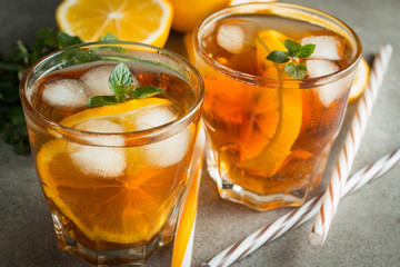 Glasses of cold ice tea with lemon, ice, mint on background. Homemade lemonade. Spring and summer drinks and beverages concept.