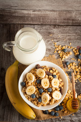 Healthy breakfast concept with oat flakes and fresh berries on rustic background. Food made of granola and muesli. Healthy banana smoothie with blackberries, honey and milk.