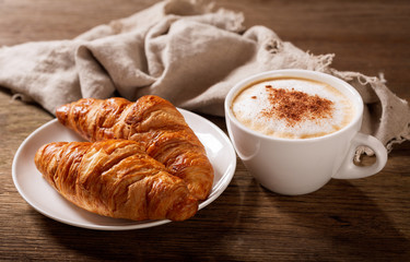 cup of cappuccino coffee and croissants