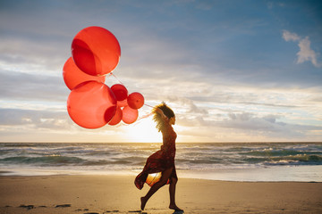 Woman running on the beach with balloons - Powered by Adobe