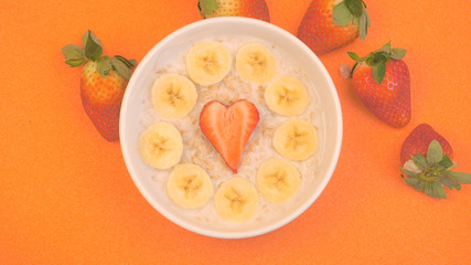 Ceramic bowl with oatmeal porridge with bananas and strawberry