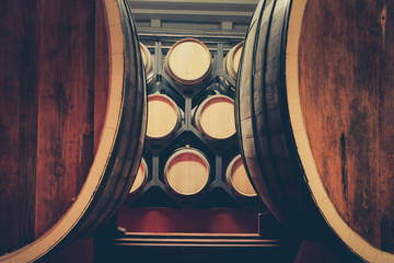 Oak barrels with cognac in dark cellar. Modern production of cognac with the observance of age-old...