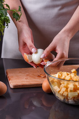 young woman in a gray apron cleans the boiled egg