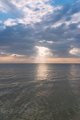 Sunbeams or sun rays peeking through the clouds at a sunrise at sea