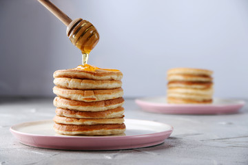 Stack of Pancakes with pouring honey. decorating concept on light background