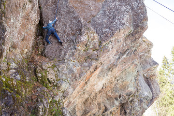 Little girl engaged in the sports climbing the vertical natural rock